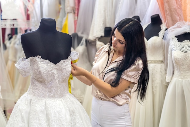 Femme mesurant la robe de mariée sur mannequin en salon