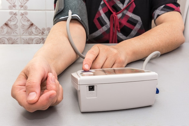 Photo une femme mesure sa tension artérielle avec un appareil électronique autonome