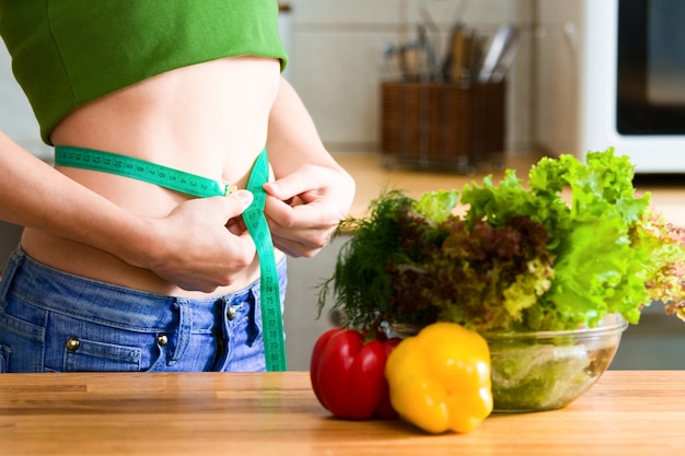 Femme mesure son ventre dans la cuisine