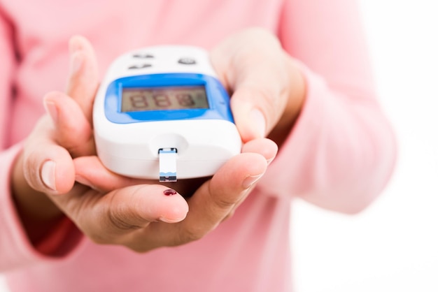 Femme mesurer le niveau de test de glucose avec du sang sur le doigt