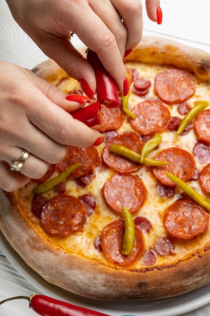 Une femme met du pepperoni sur une pizza