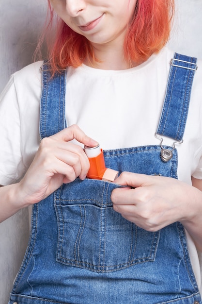 Une femme met un inhalateur dans sa poche pour traiter l'asthme. Journée mondiale de l'asthme. Concept de soins d'allergie