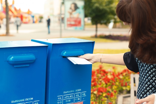 Femme met des lettres dans la boite aux lettres