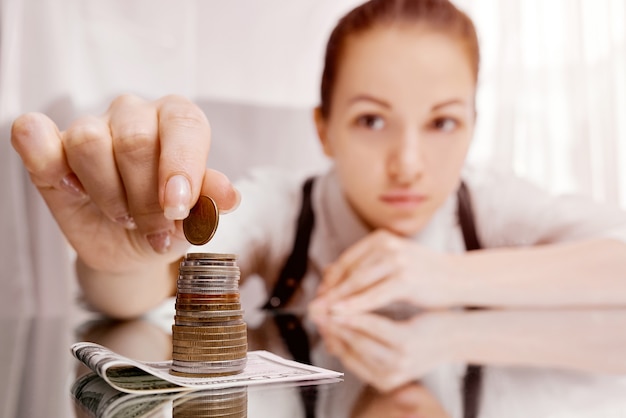 Une femme met des pièces dans une pile sur un billet de banque sur la table. Il collecte de l'argent. Son capital. . photo de haute qualité