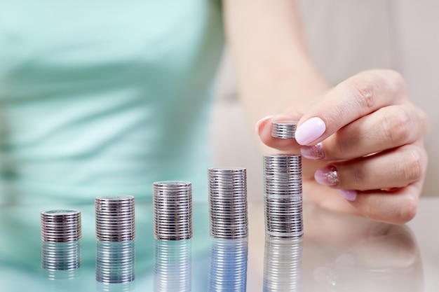 La femme met des pièces de monnaie à une pile de pièces de monnaie