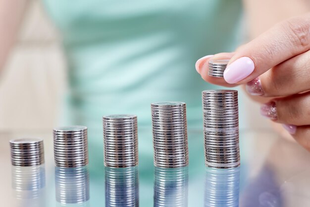 La femme met des pièces de monnaie à une pile de pièces de monnaie