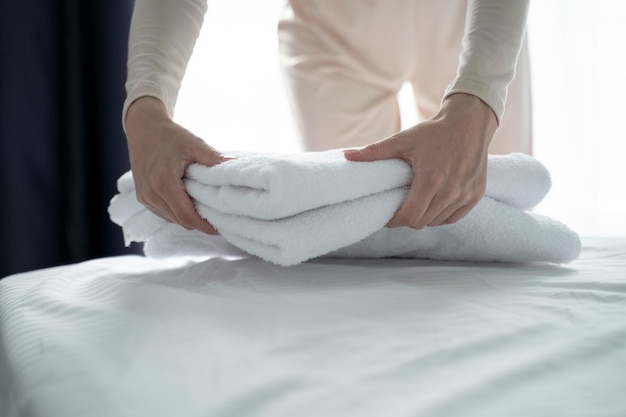 Photo une femme met des serviettes propres sur le lit dans une chambre d'hôtel pour les invités en gros plan une main de femme touche