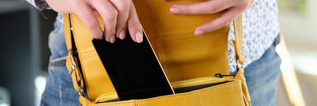 Une femme met son smartphone dans un sac jaune. Gardez le téléphone portable en sécurité et prenez des informations importantes.