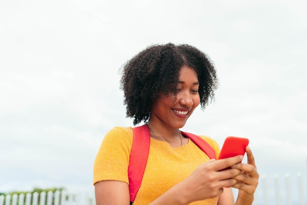 Femme métisse à l'aide d'un smartphone marchant dans la rue