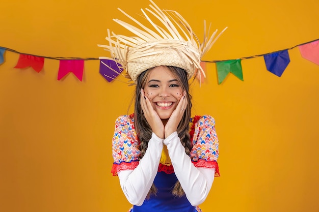 Femme métisse aux traits asiatiques portant des vêtements typiques de la Festa Junina avec des drapeaux colorés en arrière-plan