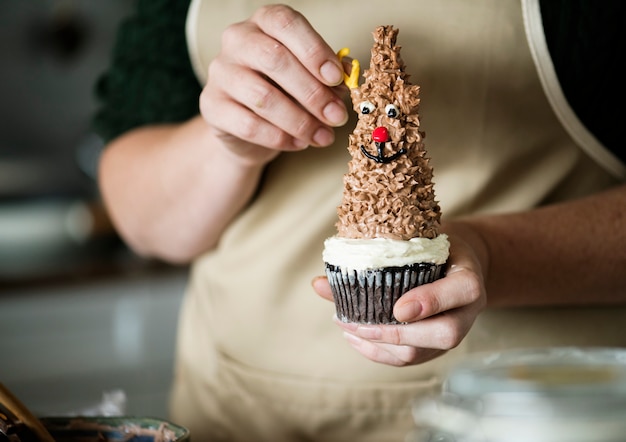 Femme mettant des bois sur un cupcake de renne