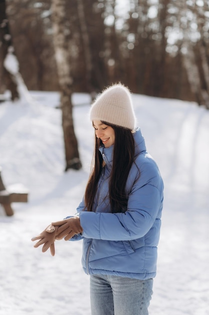 Femme mettant des gants élégants à l'extérieur dans la forêt d'hiver