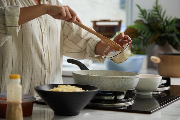 Femme mettant des oignons en dés dans une casserole