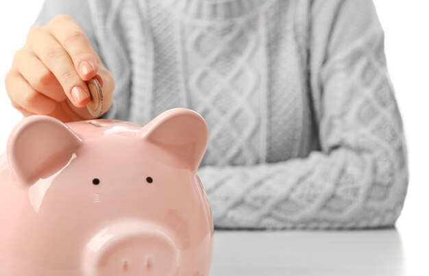 Femme mettant une pièce en euro dans une tirelire sur la table Concept d'épargne financière