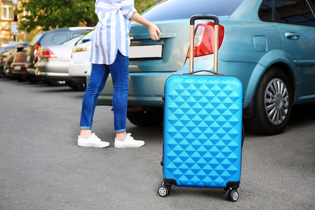 Femme mettant sa valise dans le coffre du taxi