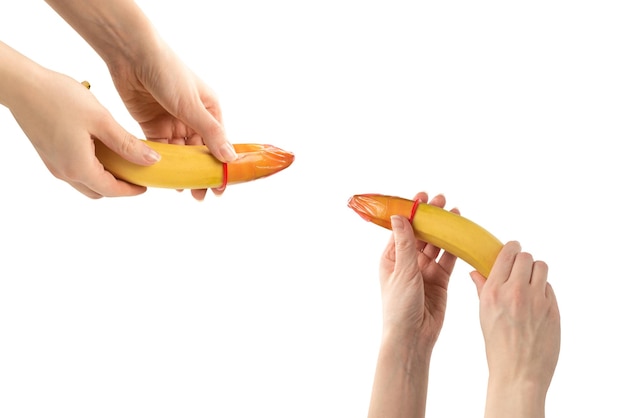 Femme mettre un préservatif sur une banane isolé sur fond blanc