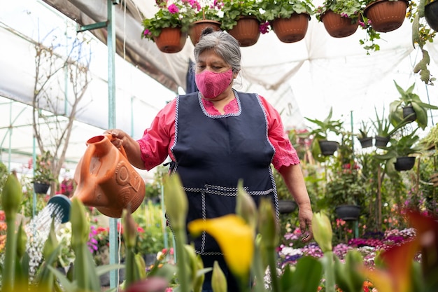 Femme mexicaine, arrosage des plantes en pépinière Xochimilco, Mexique, portant un masque facial, nouvelle normale