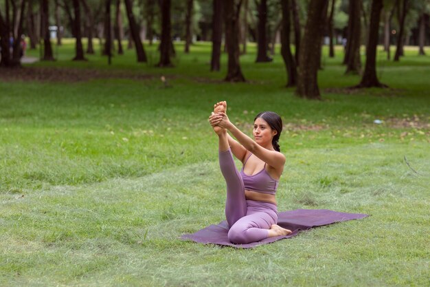 Femme mexicaine faisant des exercices de yoga dans le parc sur l'herbe verte