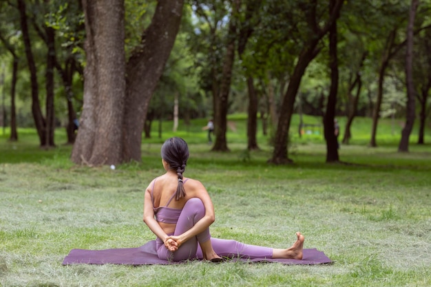 Femme mexicaine faisant des exercices de yoga dans le parc sur l'herbe verte