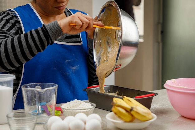 Femme mexicaine préparant une crêpe à la banane vidant la pâte dans le récipient pour la mettre au four