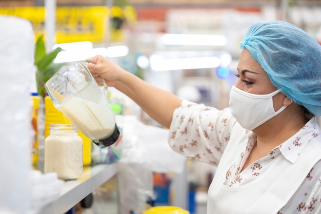 Femme Mexicaine Servant Du Jus Sur Verre, Sur Un Marché Populaire Au Mexique Portant Un Masque Facial Et Une Adaptation En Raison De La Pandémie De Coronavirus