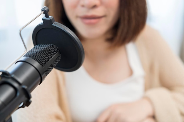 Femme avec microphone et casque parlant et enregistrant un podcast au studio