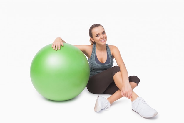 Femme mignonne assis à côté d&#39;un ballon de fitness