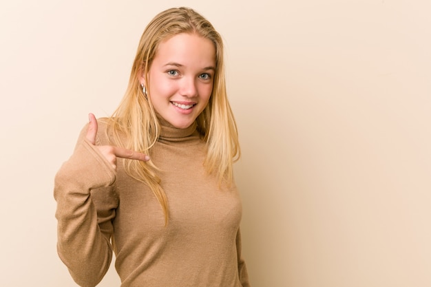 Une femme mignonne et naturelle, femme adolescente, pointant à la main un espace de copie de chemise, fier et confiant