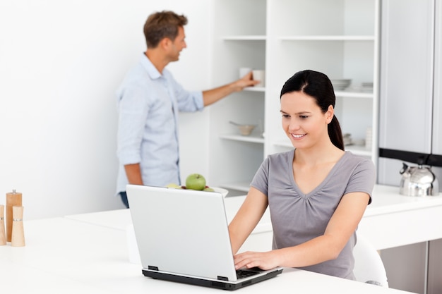 Femme mignonne travaillant sur l&#39;ordinateur portable dans la cuisine