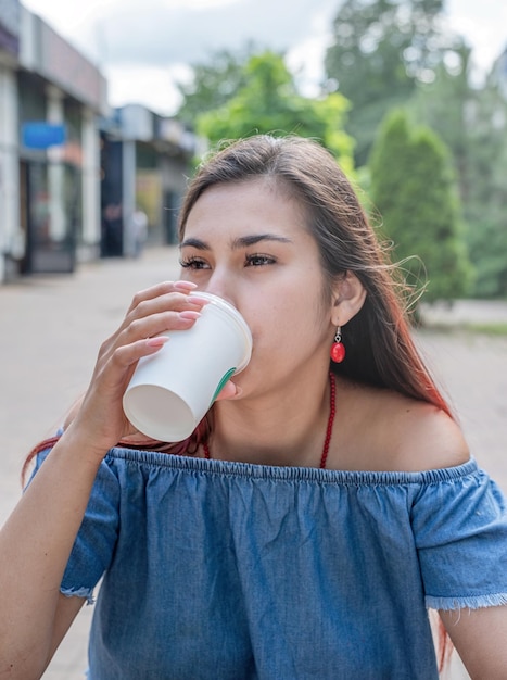 Femme millénaire élégante buvant du café au café de la rue en été