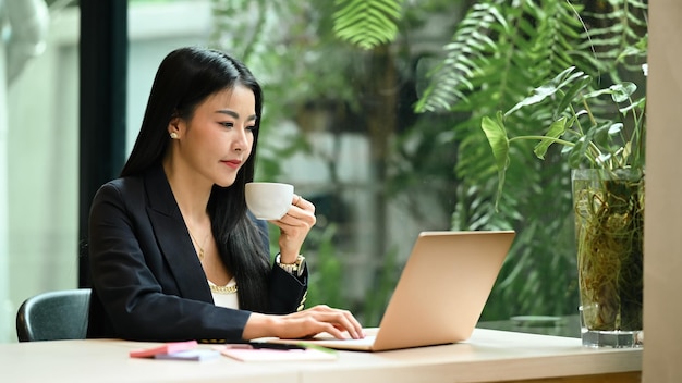 Femme millénaire réfléchie lisant des e-mails professionnels à la recherche d'informations sur un ordinateur portable