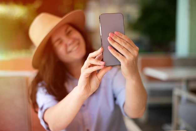 Femme millénaire souriante faisant selfie à l'extérieur de la lumière du soleil sur fond