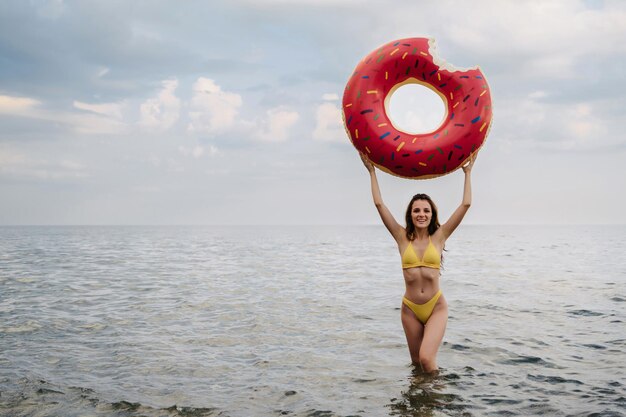 Femme mince avec un corps sexy en maillot de bain avec un cercle gonflable dans ses mains se repose sur la mer