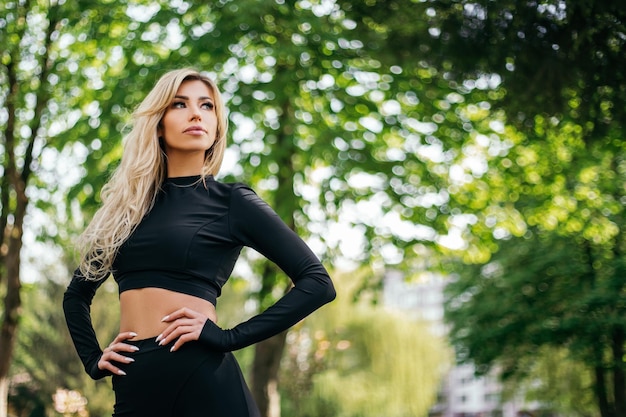 Femme mince debout et montrant le corps à l'extérieur du parc verdoyant matin regardant la caméra