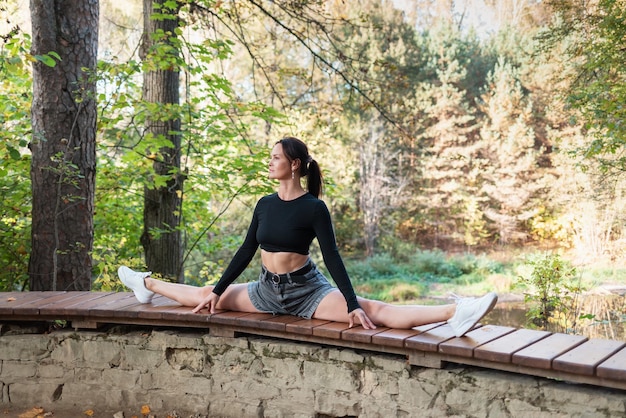 Une femme mince effectue l'exercice Samakonasana cross split training dans des vêtements décontractés