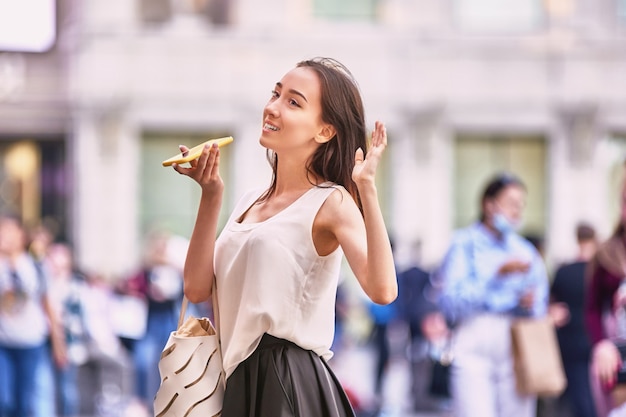 Une femme mince parle par téléphone dans une rue bondée