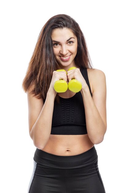 Photo une femme mince en vêtements de sport avec des haltères verts fait des exercices belle brune souriante en haut noir et leggings activité et mode de vie sain isolée sur un fond blanc verticale