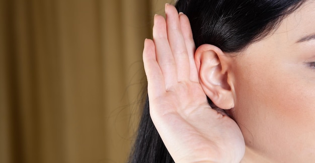 La femme a mis sa main à son oreille et écoute