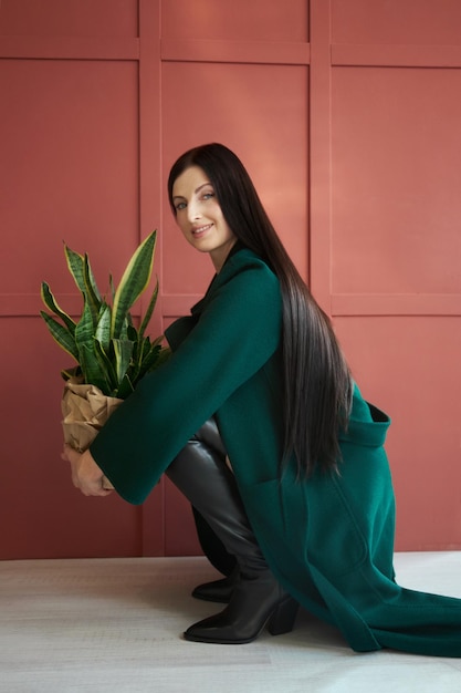 Une femme à la mode avec les cheveux longs et les jambes dans des bottes en cuir sourit des émotions joyeuses