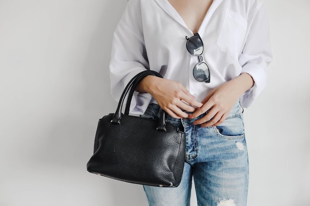 Femme à la mode et décontractée utilisant des lunettes de soleil tenant un sac à main noir Espace de copie pour la mode