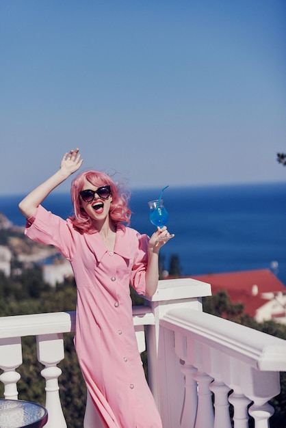 Femme à la mode dégustant un cocktail coloré sur la terrasse de l'hôtel avec vue panoramique Concept de relaxation