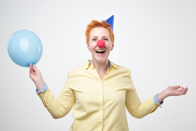 La femme de mode envoie un baiser d'air avec des ballons colorés sur le fond bleu