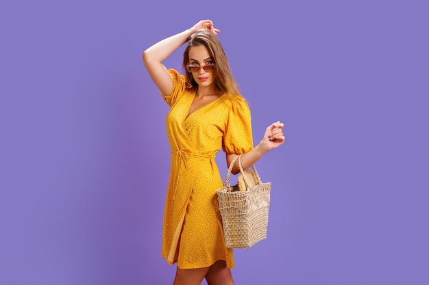 Femme à la mode en jolie robe jaune et sac à main en paille mode printemps été photo