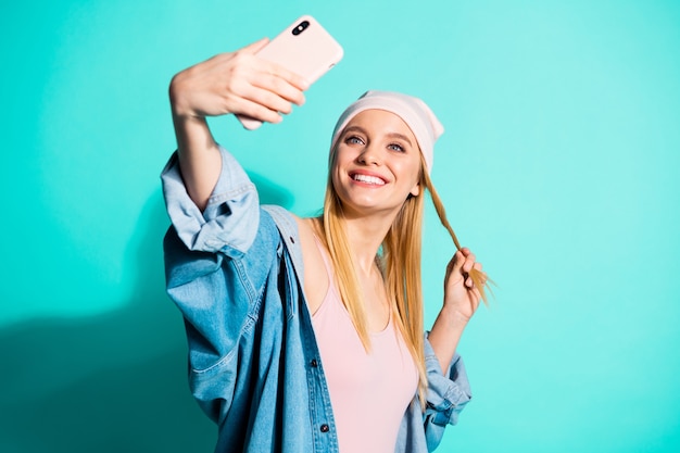 Femme à la mode posant contre le mur bleu