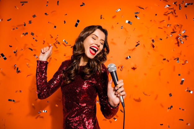 Femme à la mode posant contre le mur orange