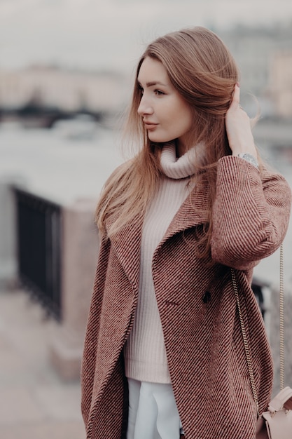 Femme à la mode regarde de côté, porte un manteau chaud à la mode