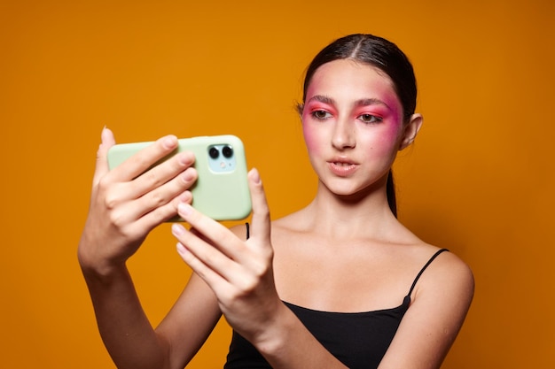 Femme à la mode regarde le téléphone maquillage lumineux posant des émotions de mode fond isolé inchangé