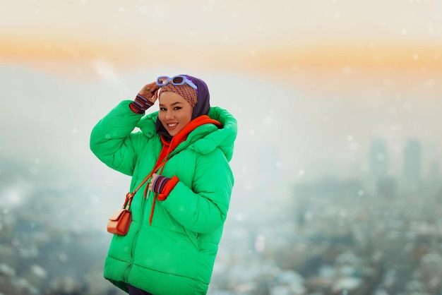 Femme moderne en hijab avec veste verte posant un jour d'hiver