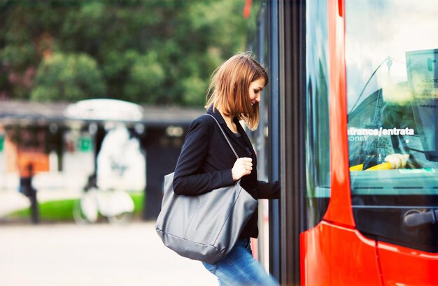 Une femme monte dans un bus et s'apprête à en descendre.