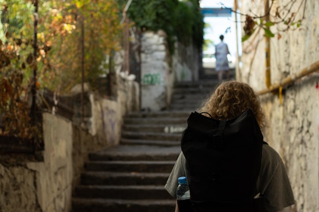 Une femme monte les escaliers dans une ville touristique avec un sac à dos Vue arrière de la fille Copier le voyage dans l'espace